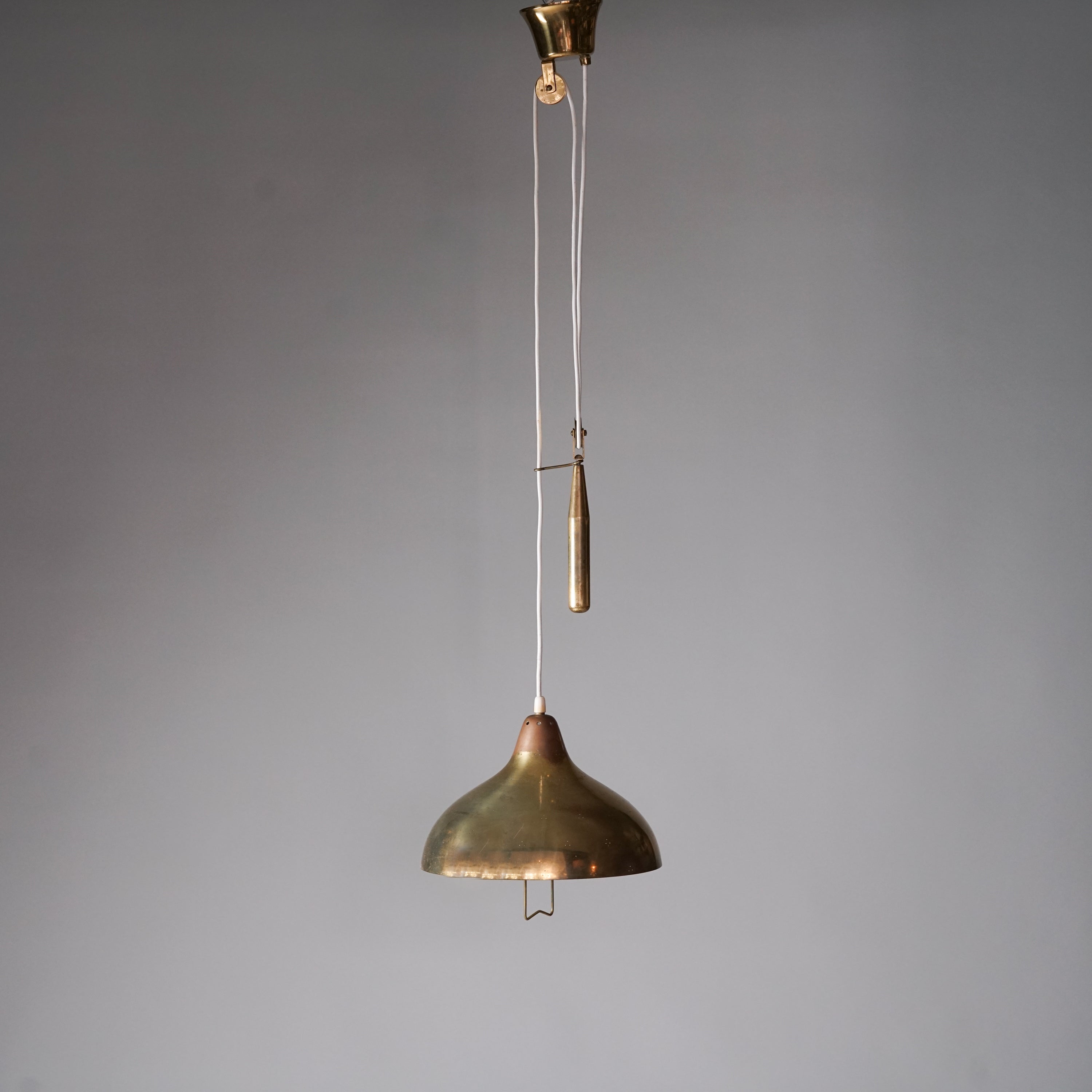 Brass ceiling light with counterweight mechanism. The shade features small three-hole clusters that reflect light and has a handle in the middle.